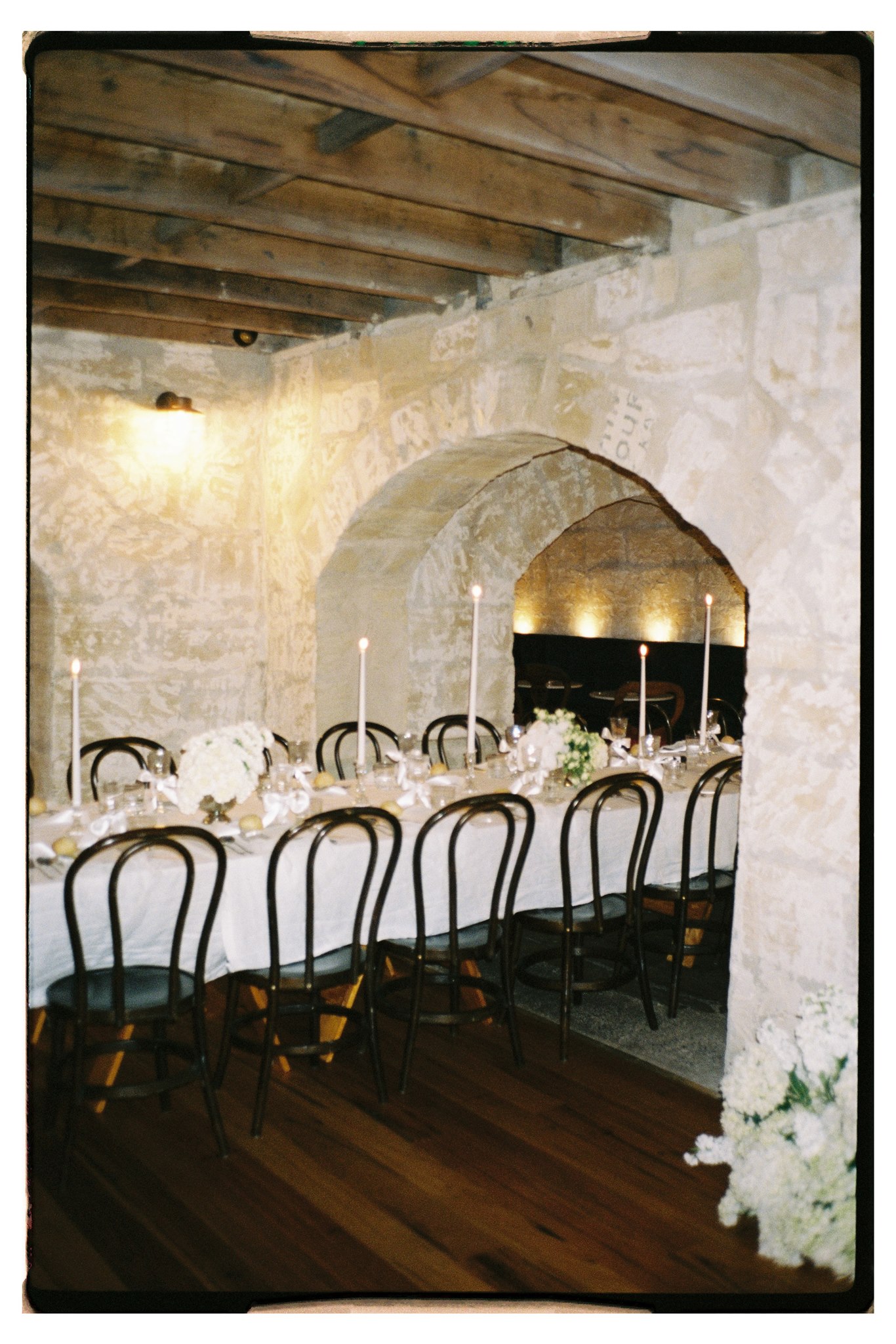 Elegant tablescape featuring pearl-themed accents, premium linens, and vintage tableware at Lauren and Bernie’s romantic intimate wedding reception at Frolic Lane, showcasing rustic sandstone arches in the background. 35mm film wedding photography.