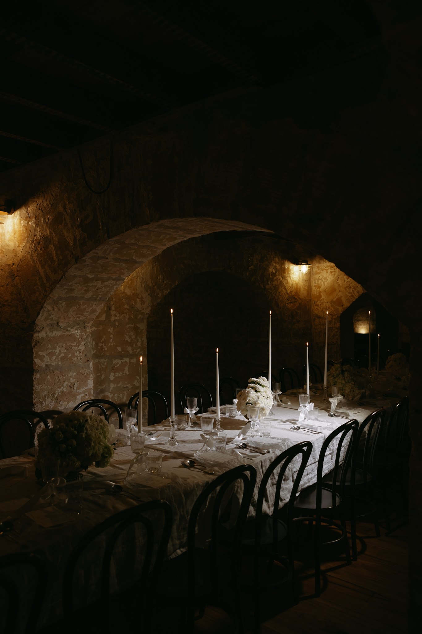 Elegant tablescape featuring pearl-themed accents, premium linens, and vintage tableware at Lauren and Bernie’s romantic intimate wedding reception at Frolic Lane, showcasing rustic sandstone arches in the background. 35mm film wedding photography.