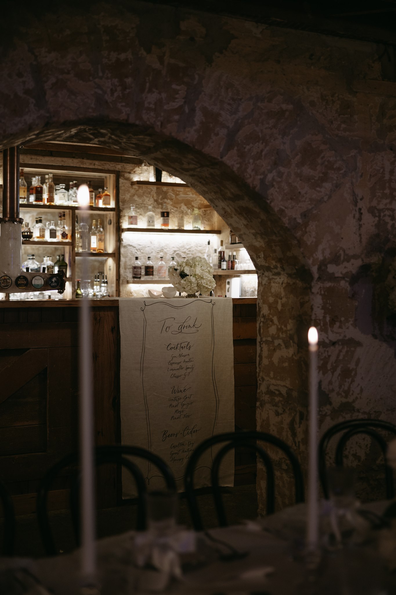 Elegant tablescape featuring pearl-themed accents, premium linens, and vintage tableware at Lauren and Bernie’s romantic intimate wedding reception at Frolic Lane, showcasing rustic sandstone arches in the background. 35mm film wedding photography.